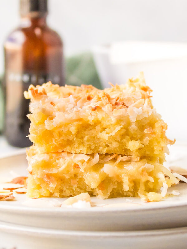 two almond coconut bars stacked on plate