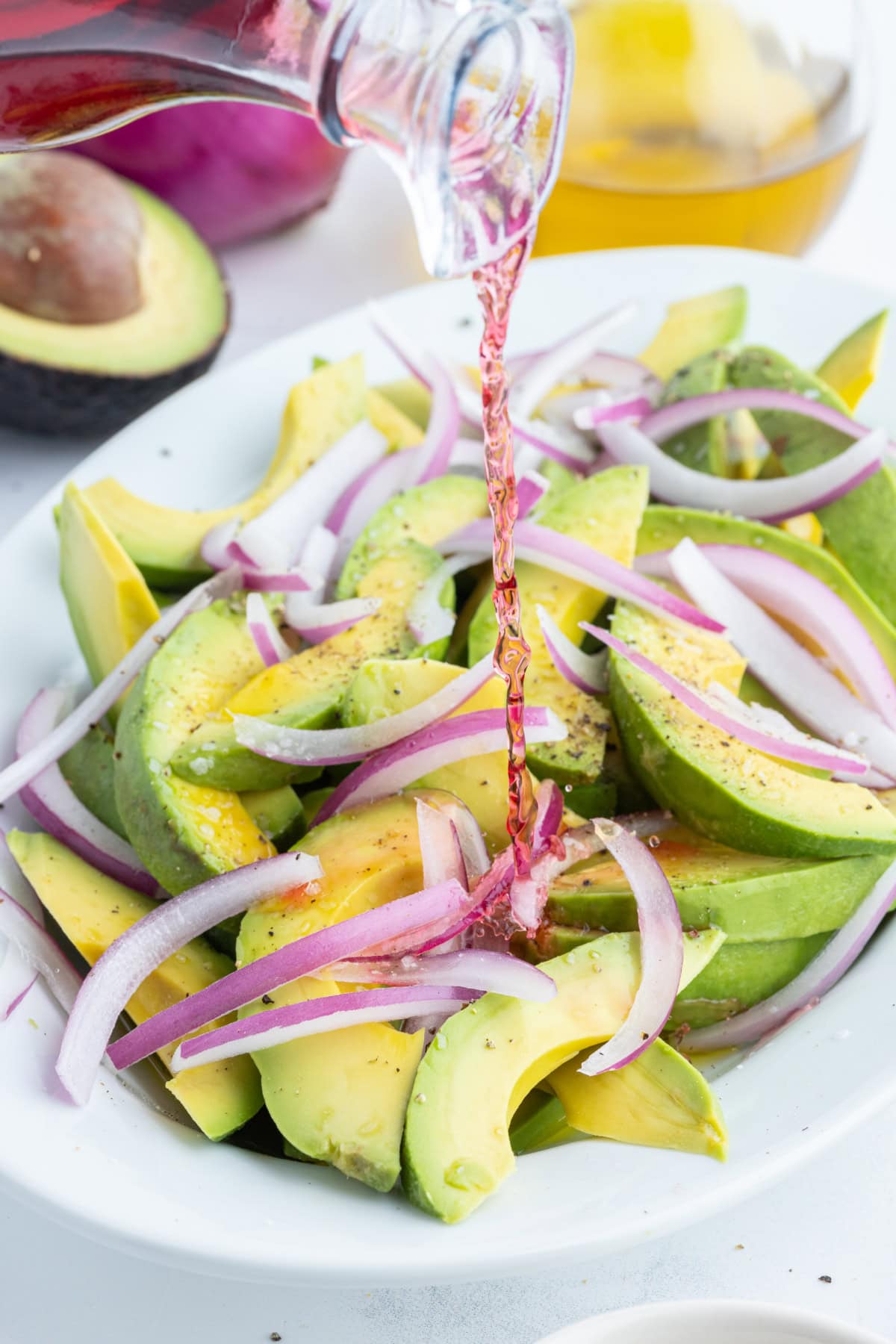 pouring dressing onto avocado and onion salad