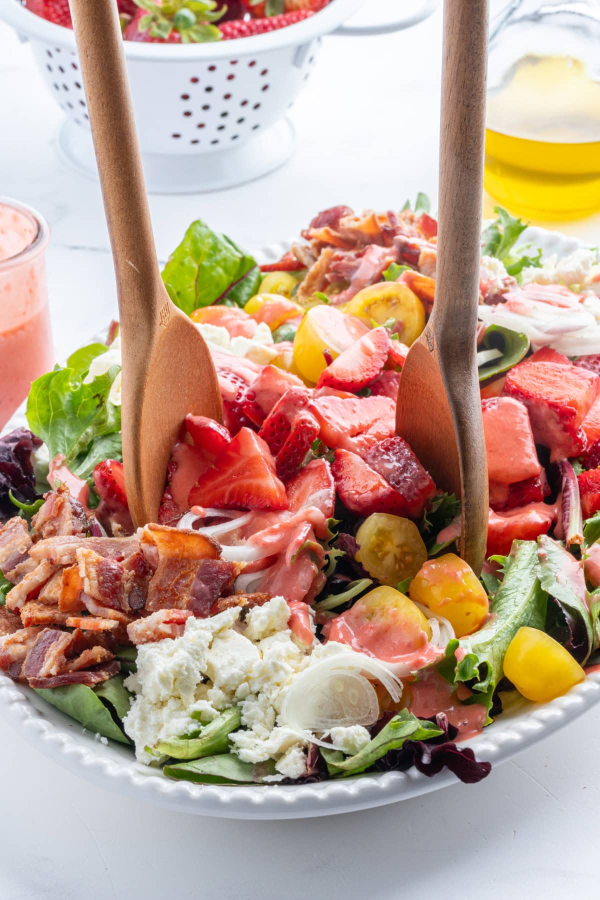 salad servers in bowl of berry bacon and tomato salad