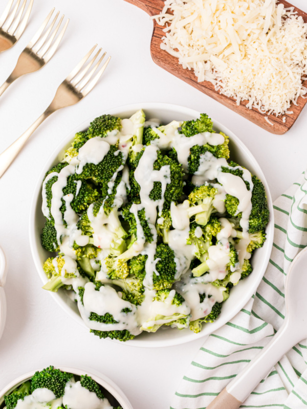 overhead shot of bowl of broccoli with two cheese sauce drizzled on top