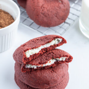 cheesecake stuffed red velvet cookies stacked and broken open to see inside