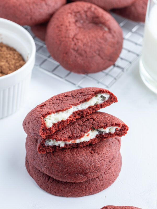 cheesecake stuffed red velvet cookies stacked and broken open to see inside