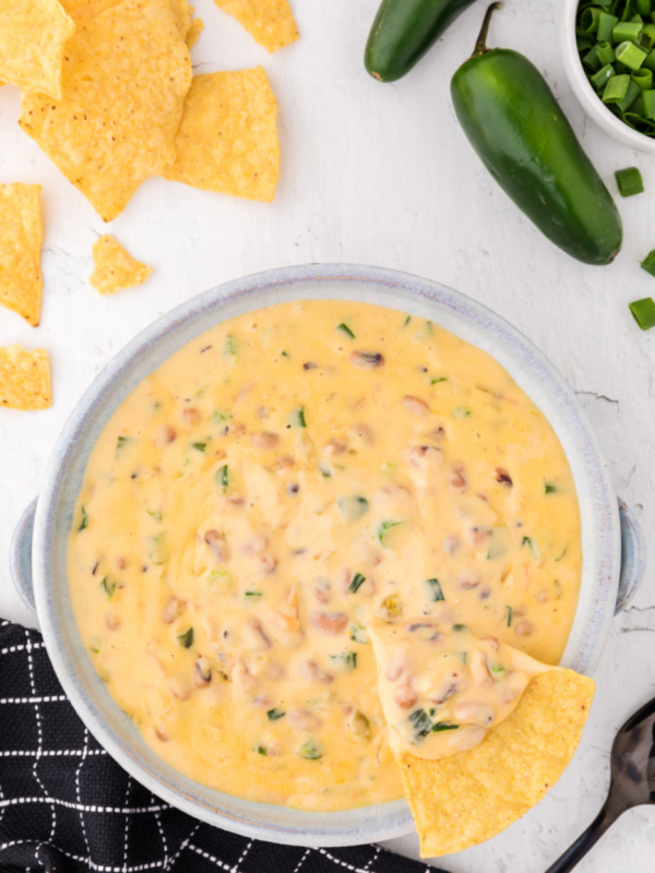 cheesy black eyed pea dip in a bowl with a chip dunked in