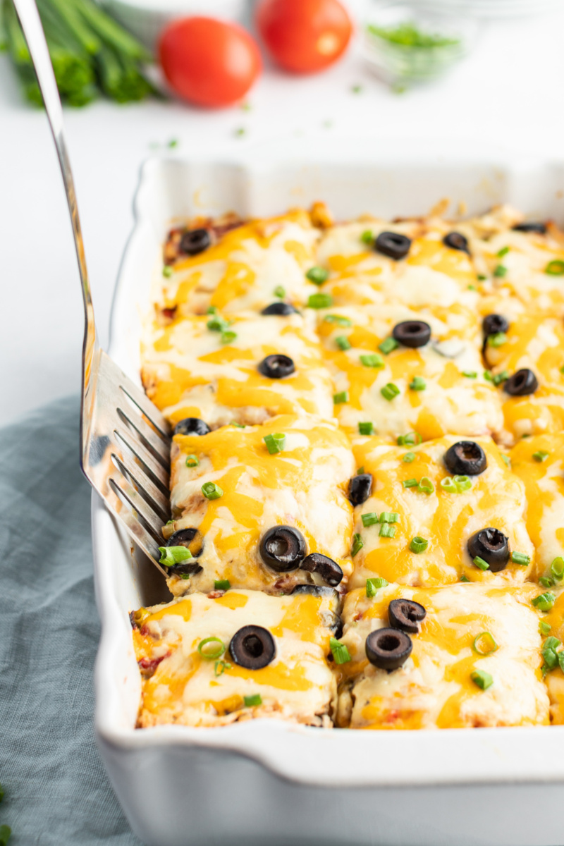 chicken enchilada casserole in a white dish with spatula