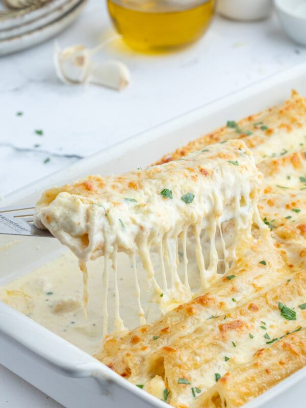 spatula lifting up chicken manicotti alfredo out of pan