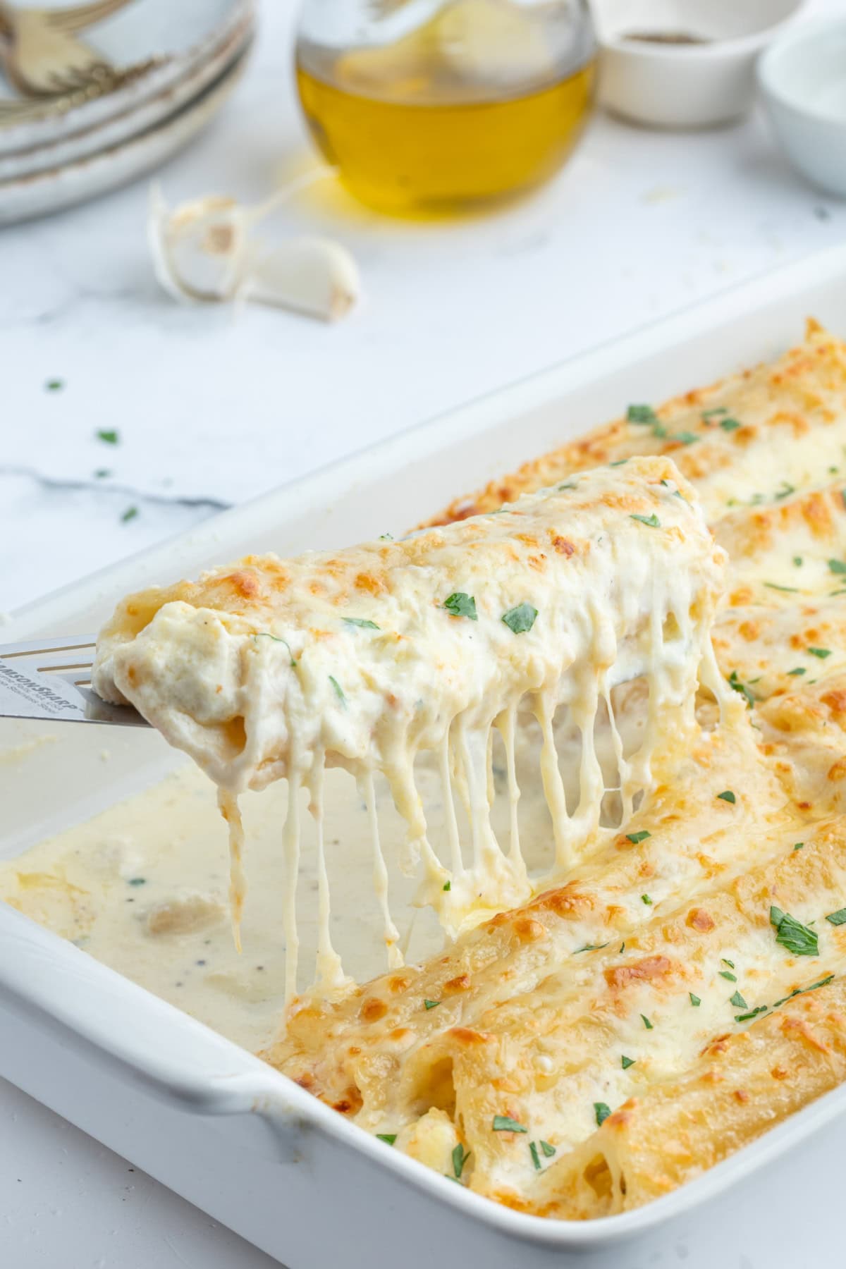 spatula lifting up chicken manicotti alfredo out of pan