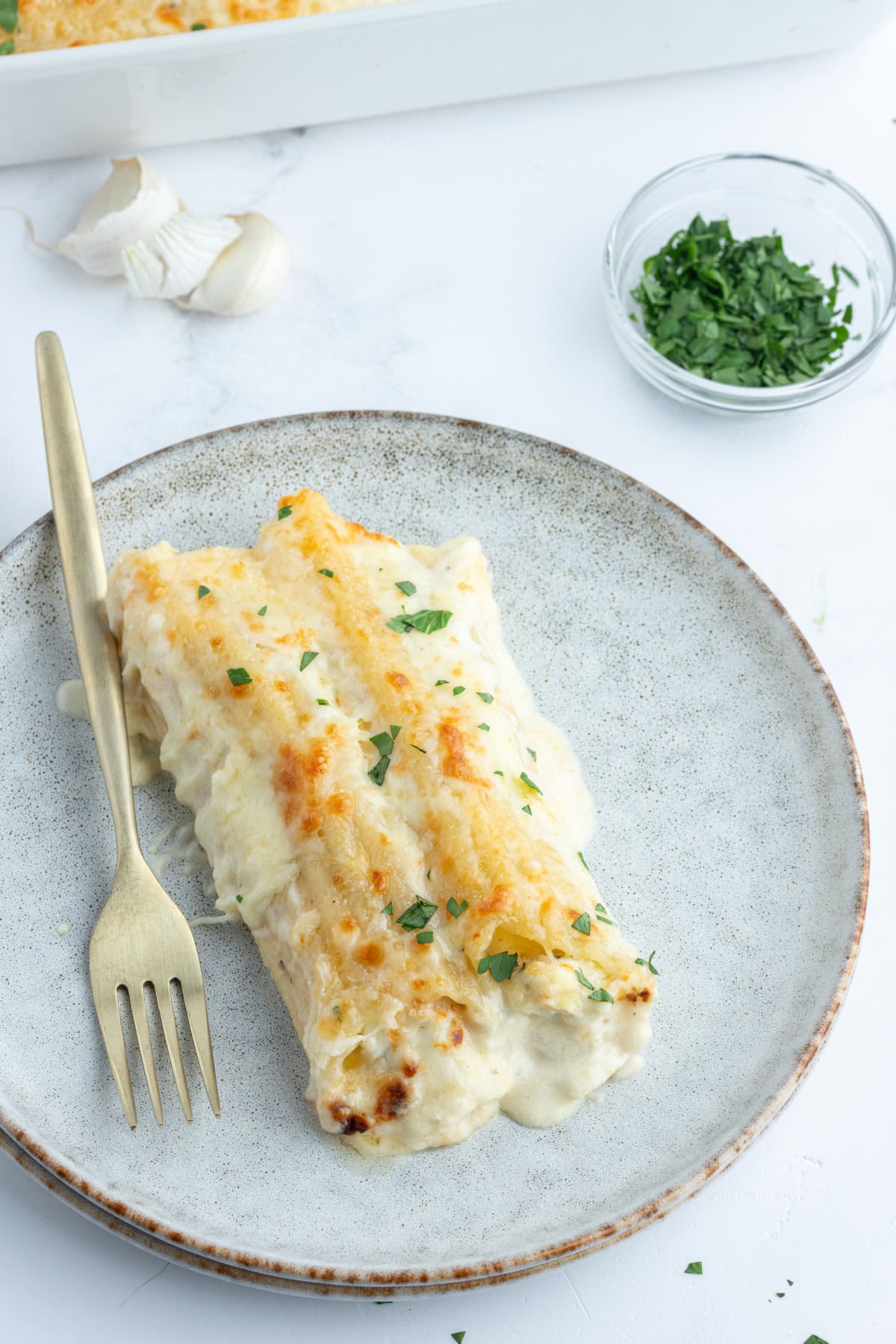 serving of chicken manicotti alfredo on plate with fork