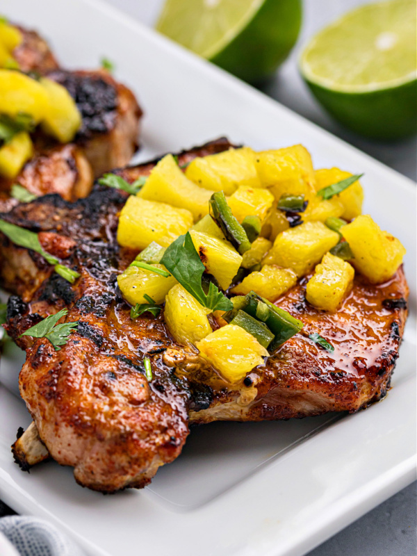 chili rubbed pork chops platter topped with grilled pineapple salsa