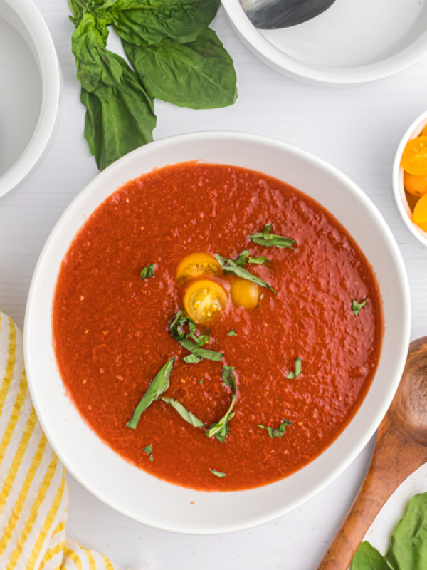 bowl of chilled tomato soup garnished with tomato and basil