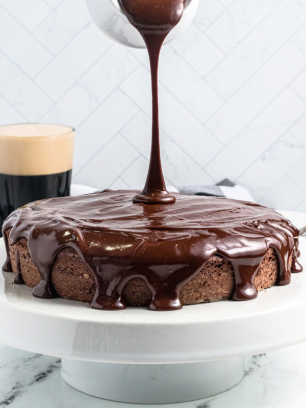 pouring chocolate glaze on top of chocolate cake