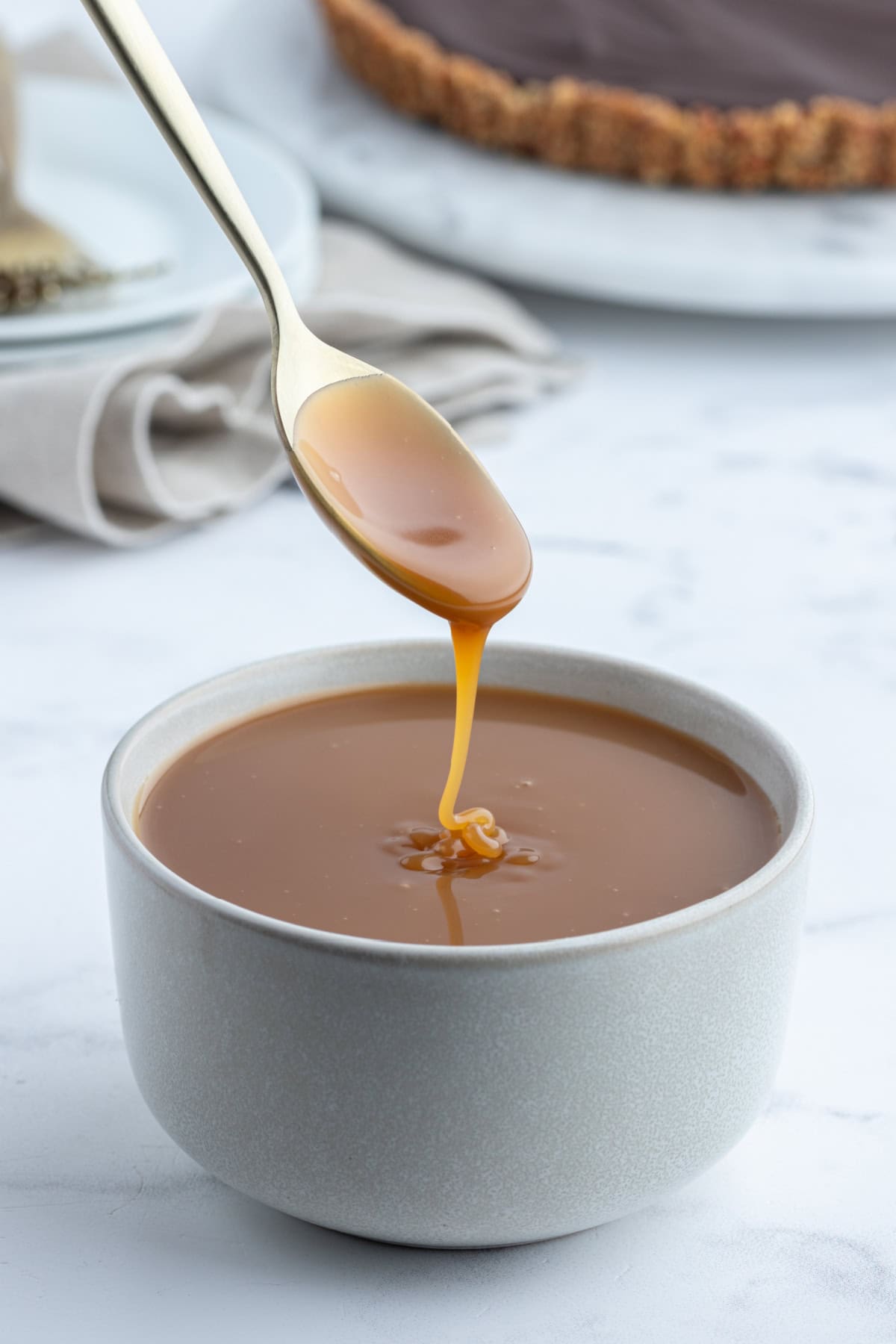 spoon coming out of bowl of caramel sauce dripping