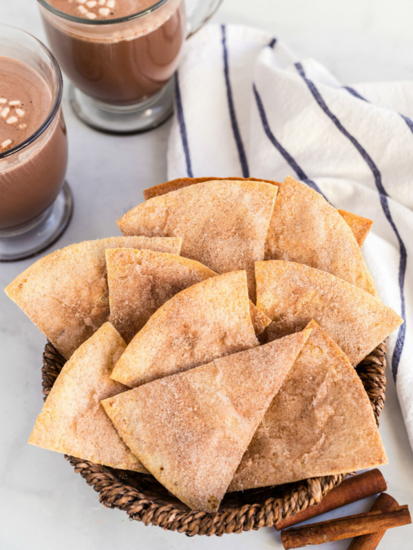 cinnamon bunuelos in a basket with hot chocolate