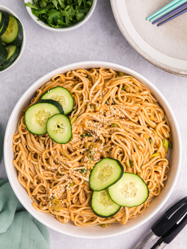 cold sesame noodles in a bowl with cucumber slices