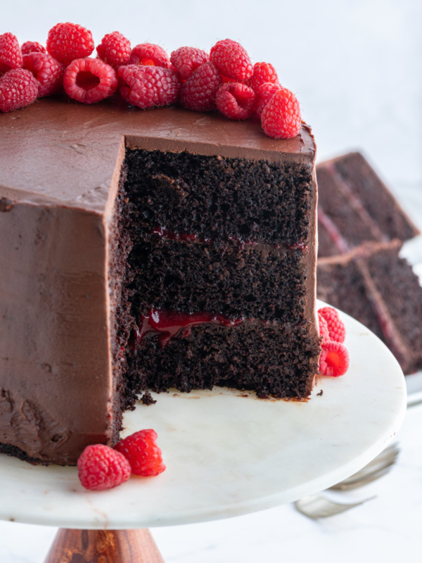 double chocolate cake with raspberry filling on cake stand with slice taken out