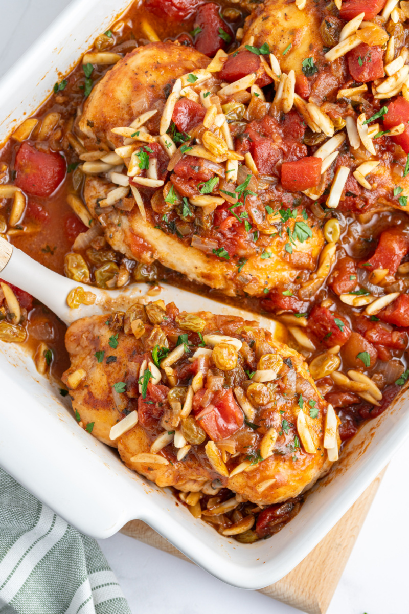 spooning out chicken from baking dish