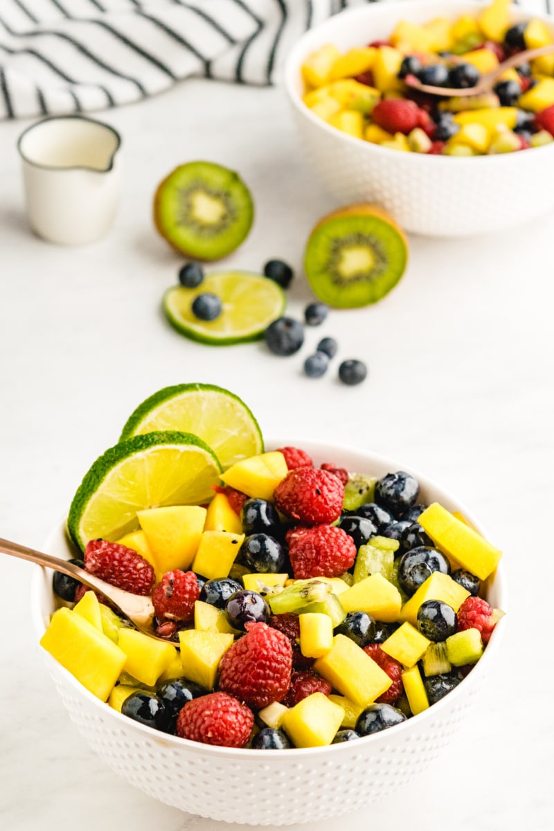 bowl of fruit salsa with spoon and lime garnish