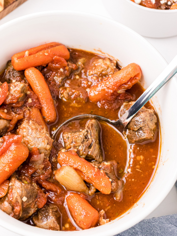 ladle of greek beef stew in a white bowl