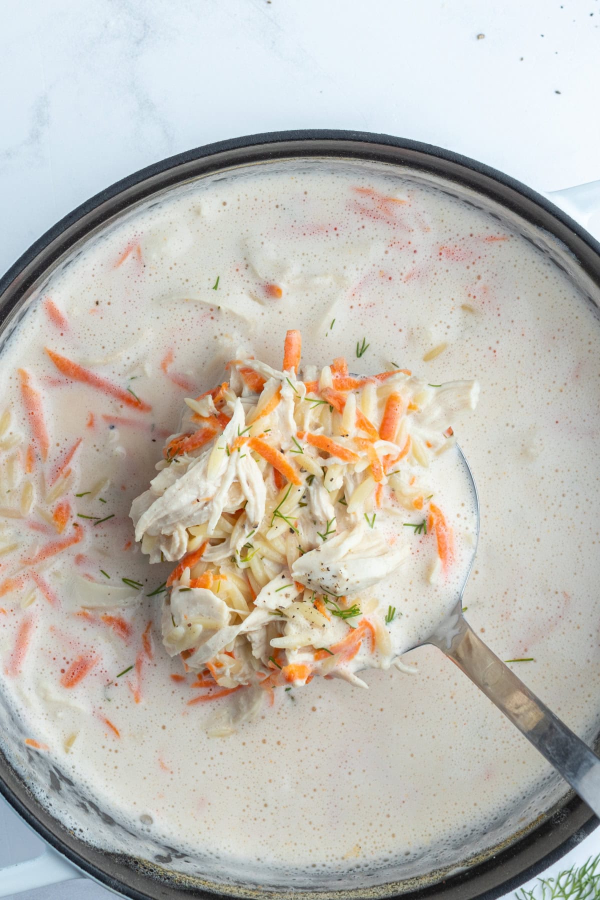 ladle sitting in pot of greek orzo and chicken soup