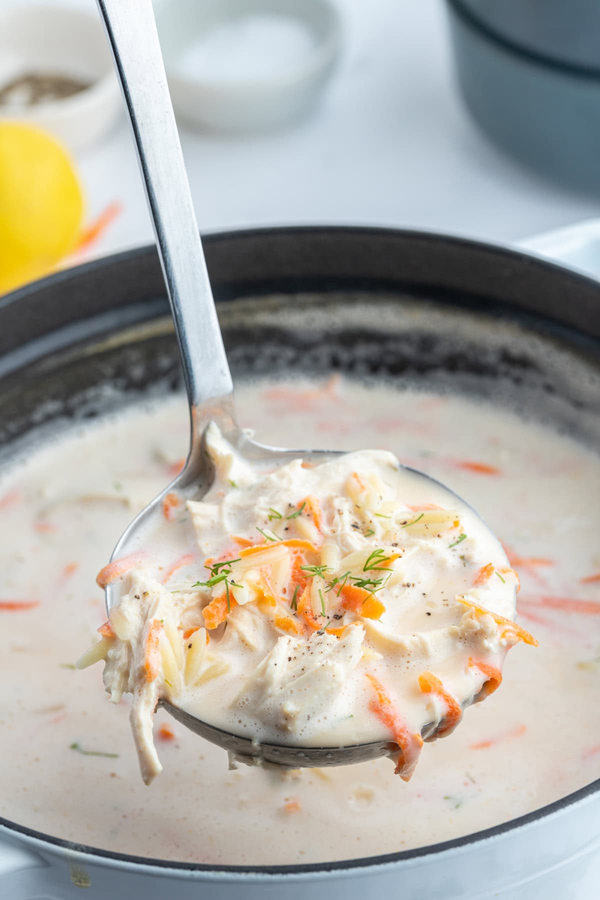 ladle full of greek orzo and chicken soup over pot of soup