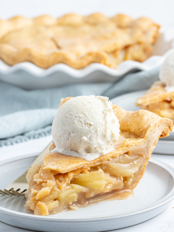 slice of maple apple pie on a plate with ice cream