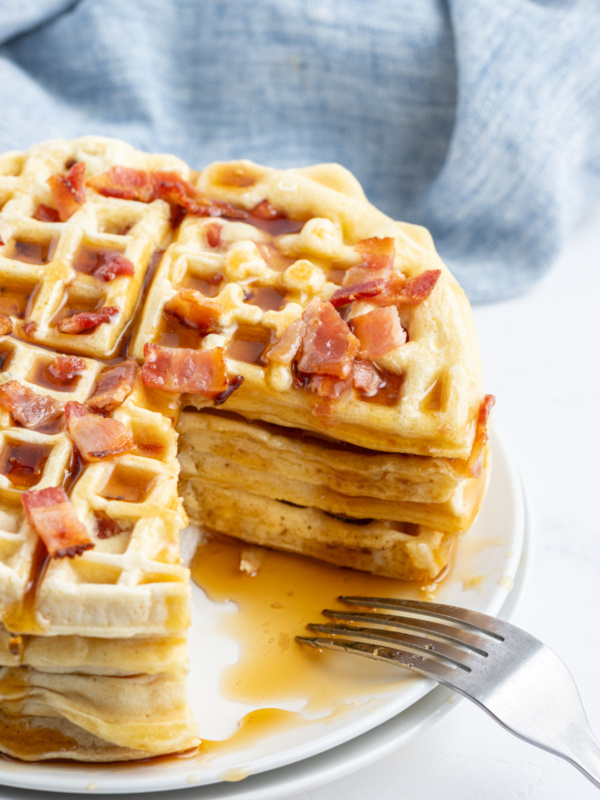 stack of maple bacon waffles with big slice taken out