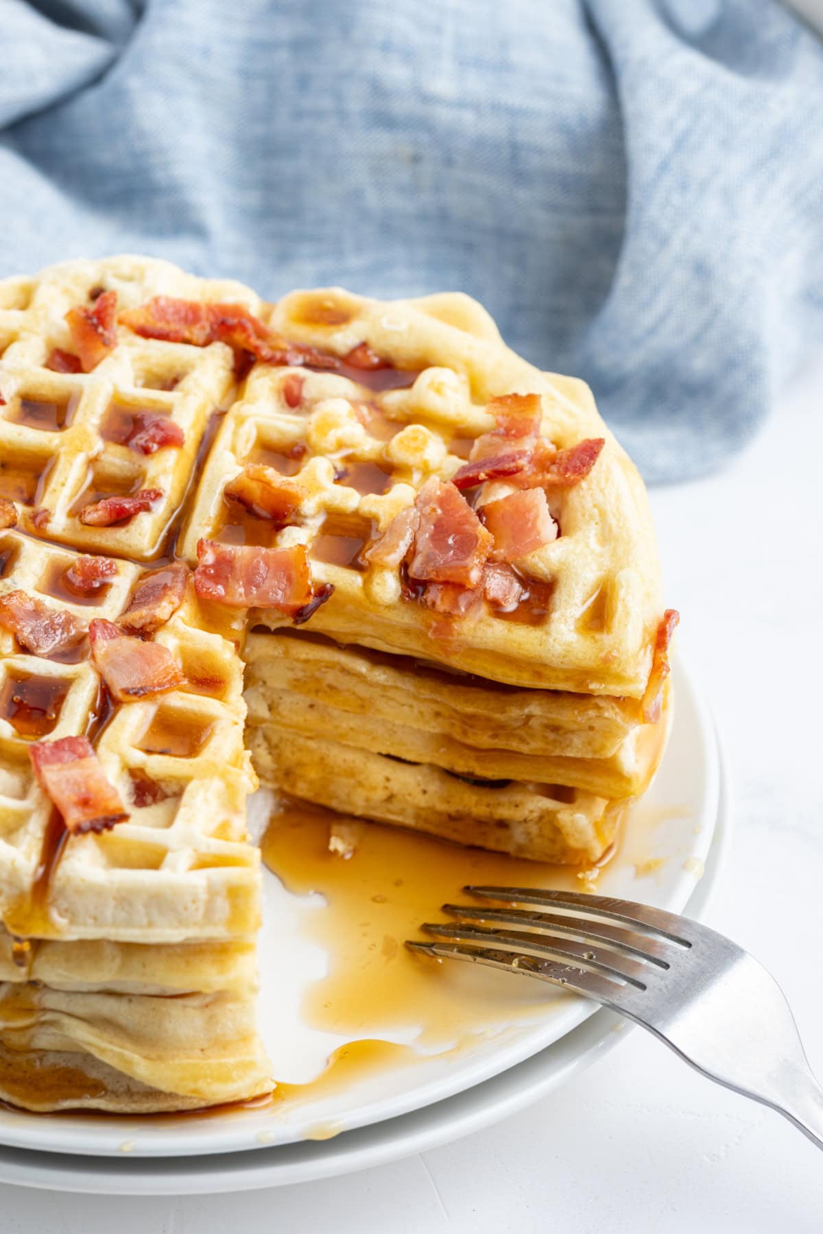 stack of maple bacon waffles with big slice taken out