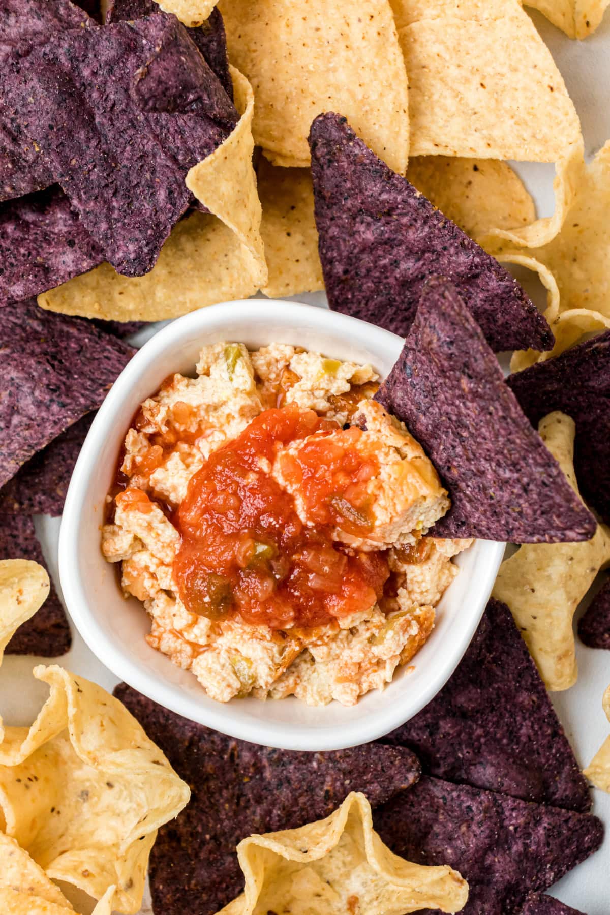 chip sitting in bowl of mexican cheesecake dip