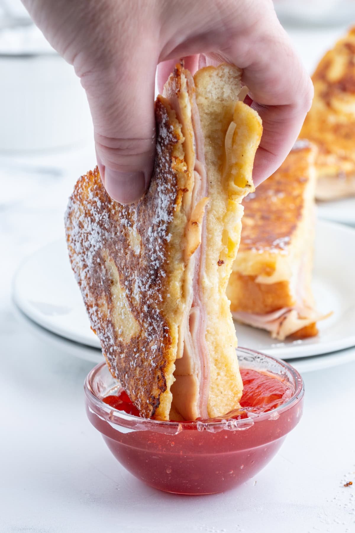 dipping monte cristo sandwich halve in jam