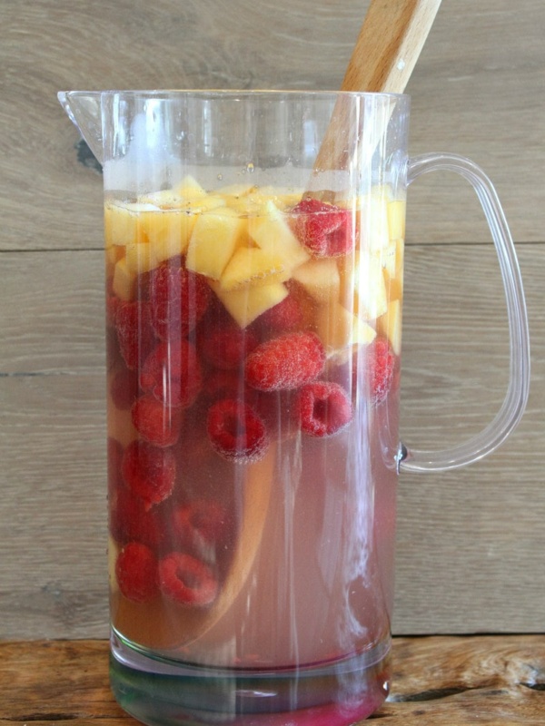 pitcher of peach and raspberry sangria with a wood backdrop