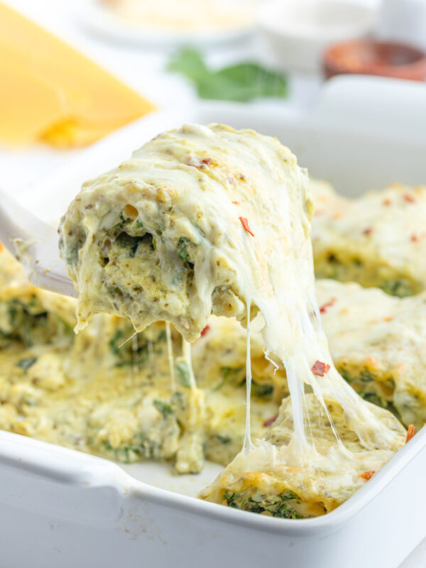 spatula pulling pesto lasagna roll from casserole dish