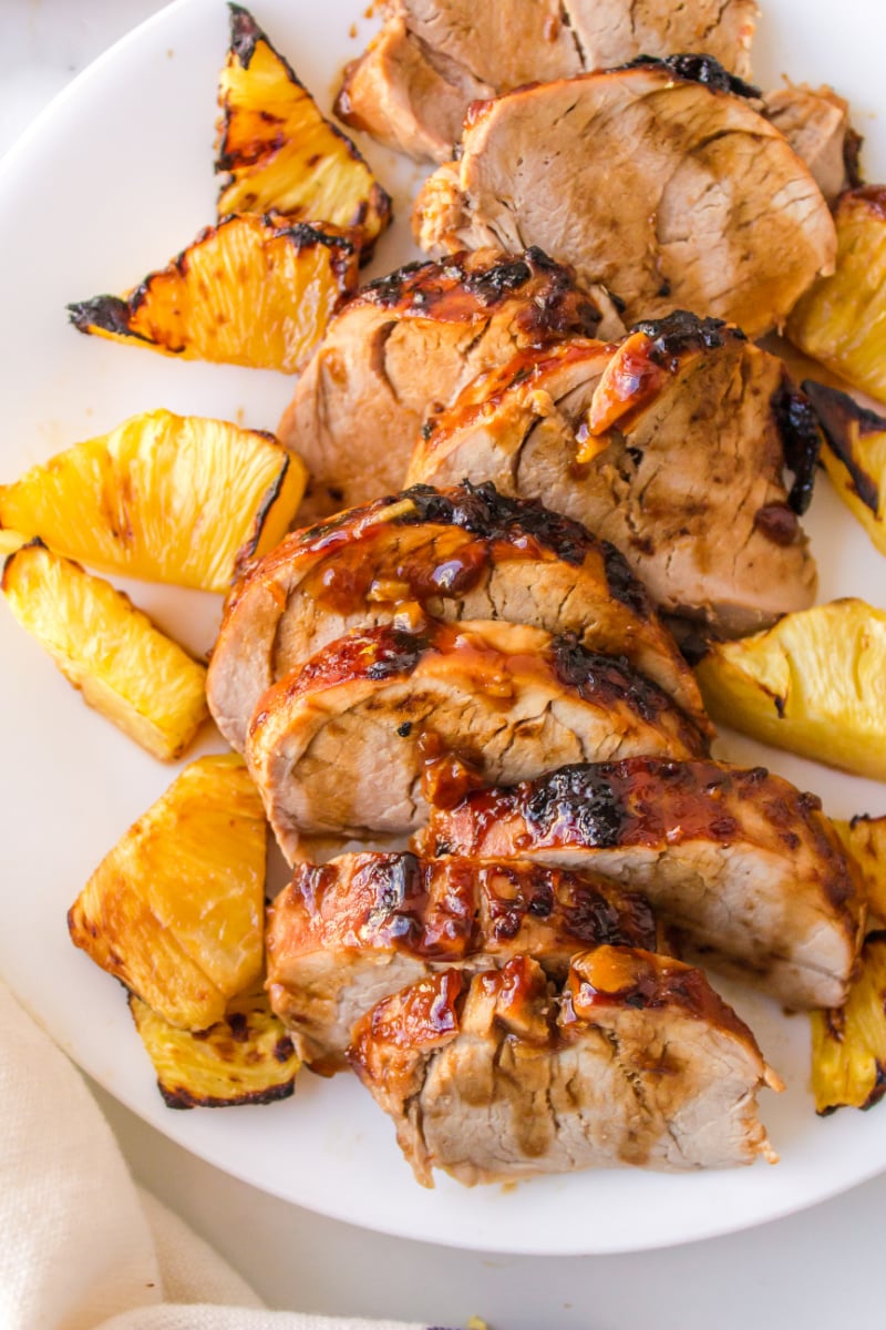 sliced pork tenderloin on a plate with pineapple