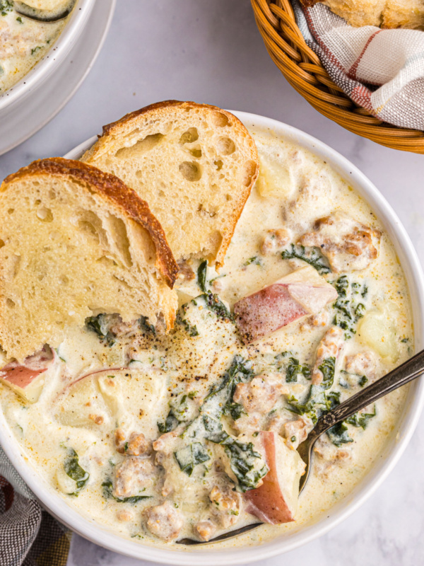 bowl of potato sausage and kale soup with slices of bread