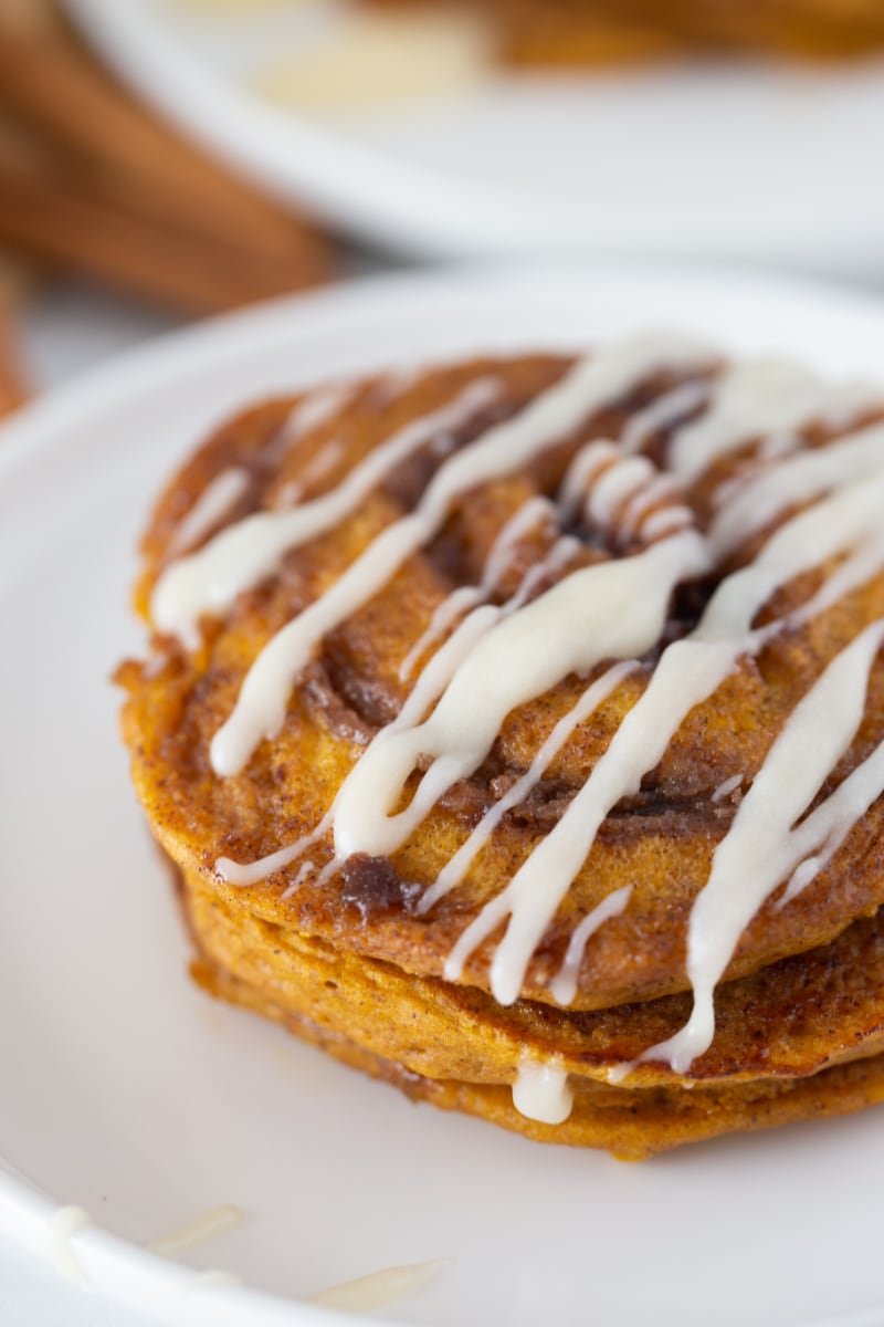 pumpkin cinnamon roll pancakes on a white plate