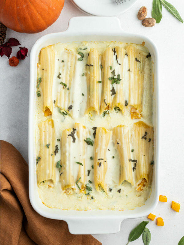 pumpkin manicotti with bechamel sauce in white casserole dish