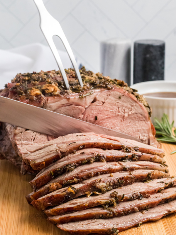 slicing leg of lamb with garlic and rosemary