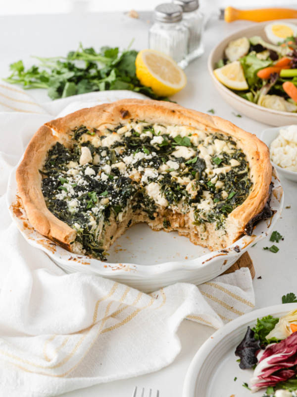 spinach caramelized onion and feta quiche with big slice taken out of it