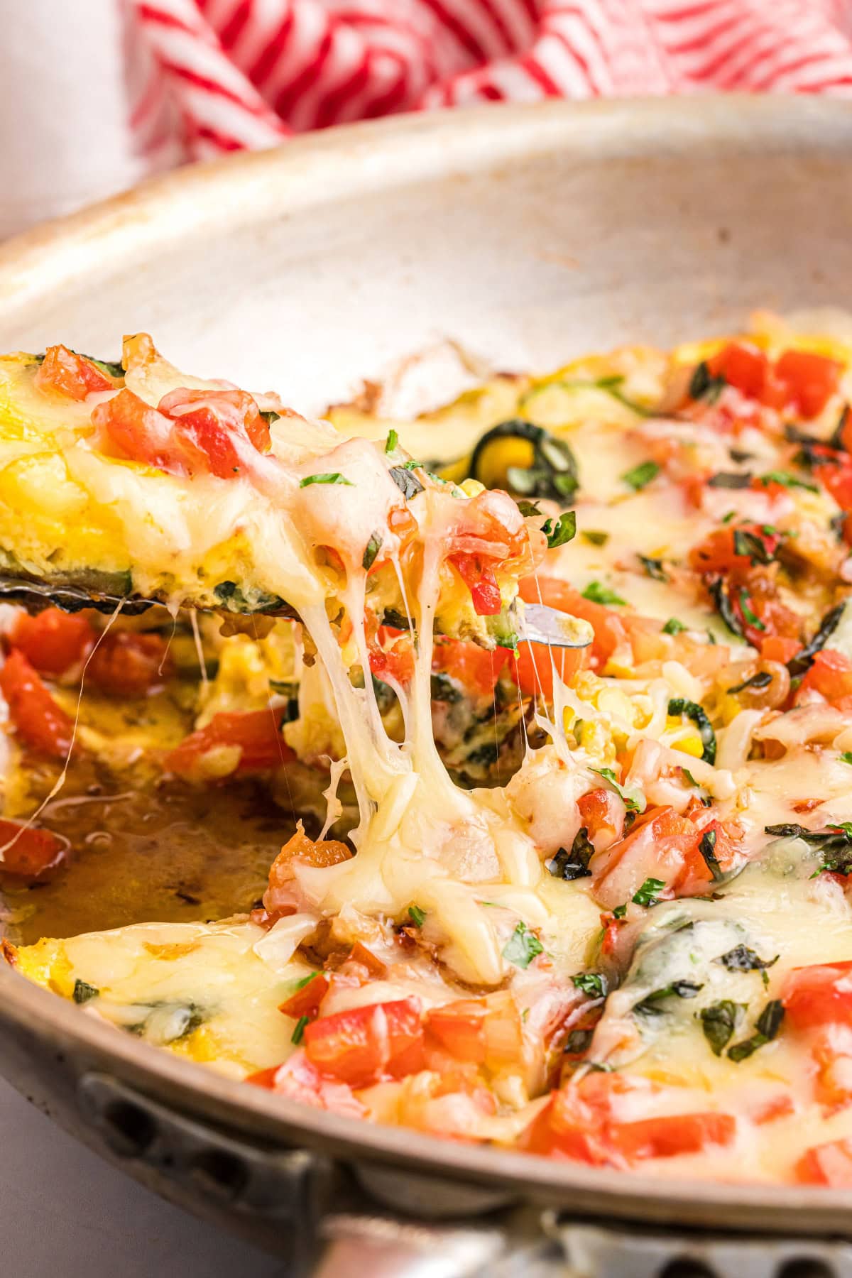 spatula picking up slice of squash and tomato oven frittata