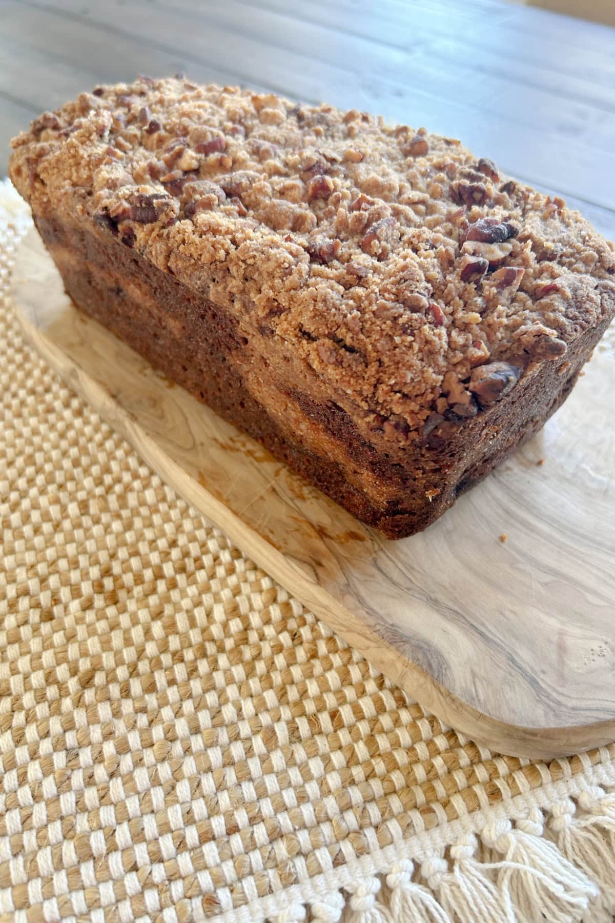 loaf of streusel banana bread sitting on bread board