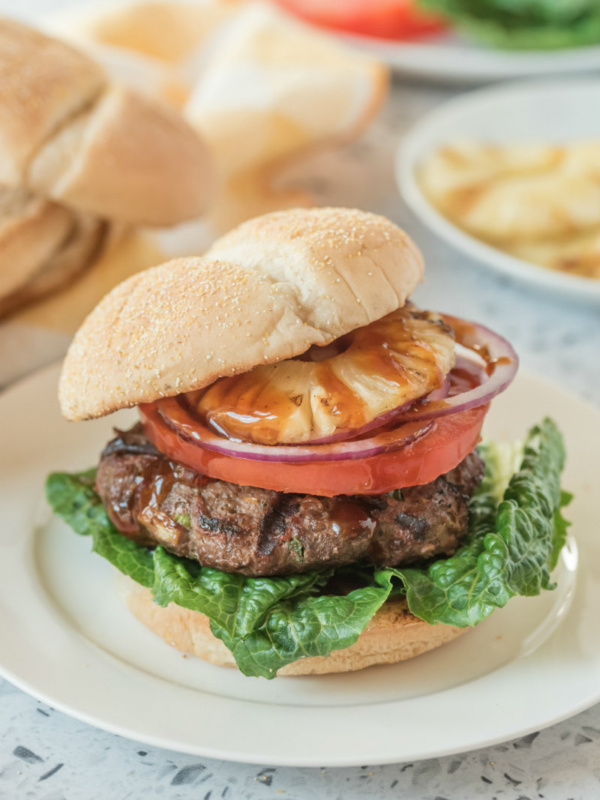 teriyaki burger with bun on top sitting on a white plate