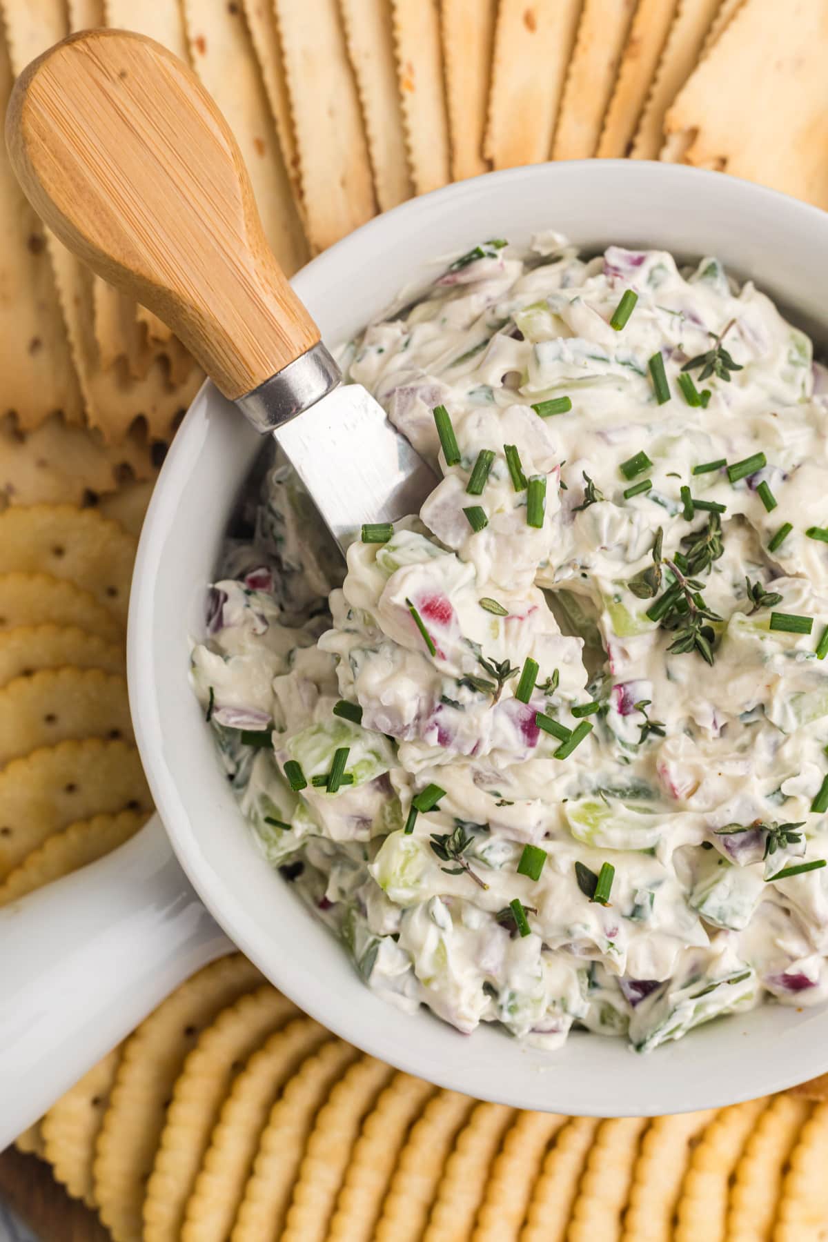 bowl of vegetable goat cheese spread surrounded by crackers