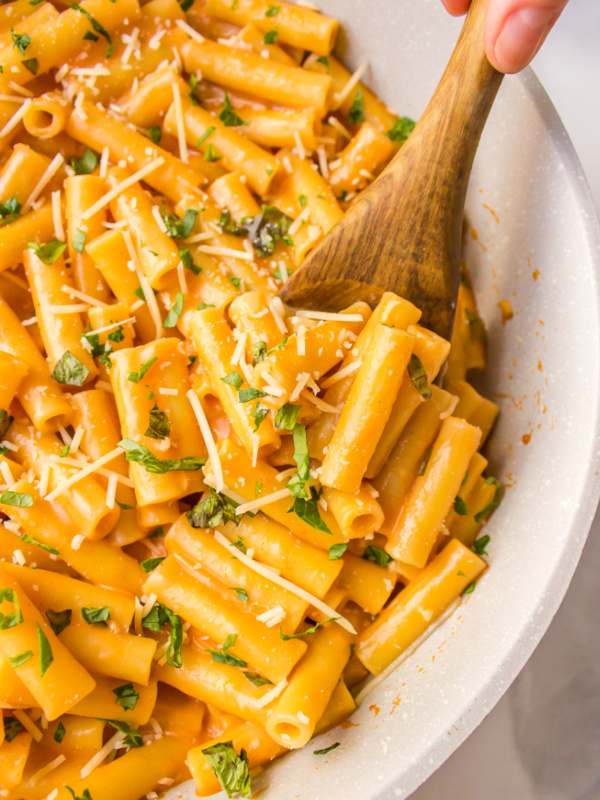 spooning ziti with vodka sauce out of skillet